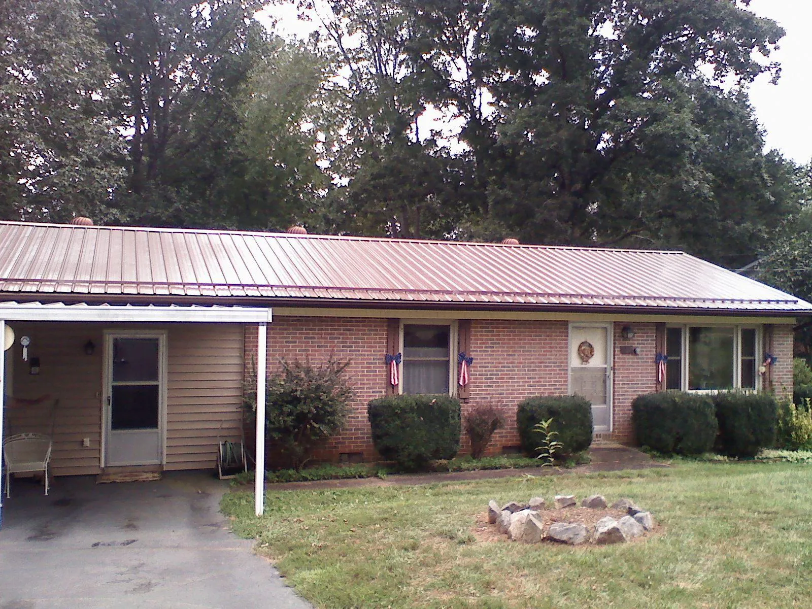 Bronze metal roof and carport on a brick ranch home — Roof Repair work by our crew in Maynard
